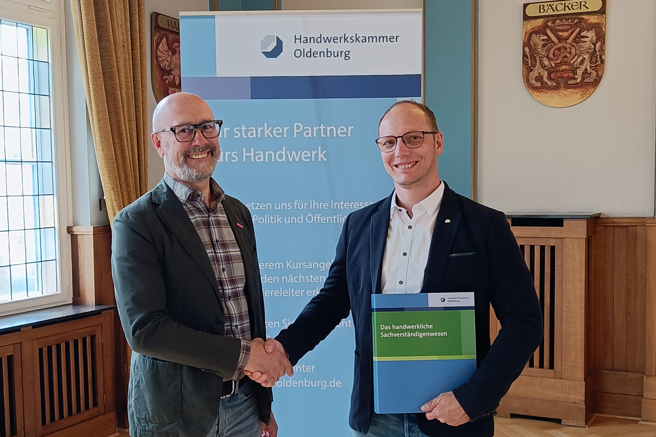 KI generiert: Zwei Männer schütteln sich vor einem Banner der Handwerkskammer Oldenburg die Hand.