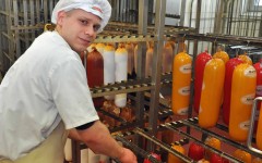 Auszubildende zur Fachverkäuferin am Bäcker-Regal in einem Bäckerei-Verkaufsraum