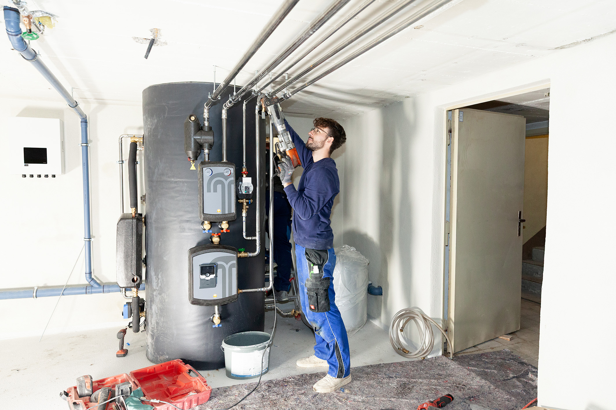 KI generiert: Eine Person arbeitet in einem Technikraum an einer Heizungs- oder Wasserleitungsanlage.
