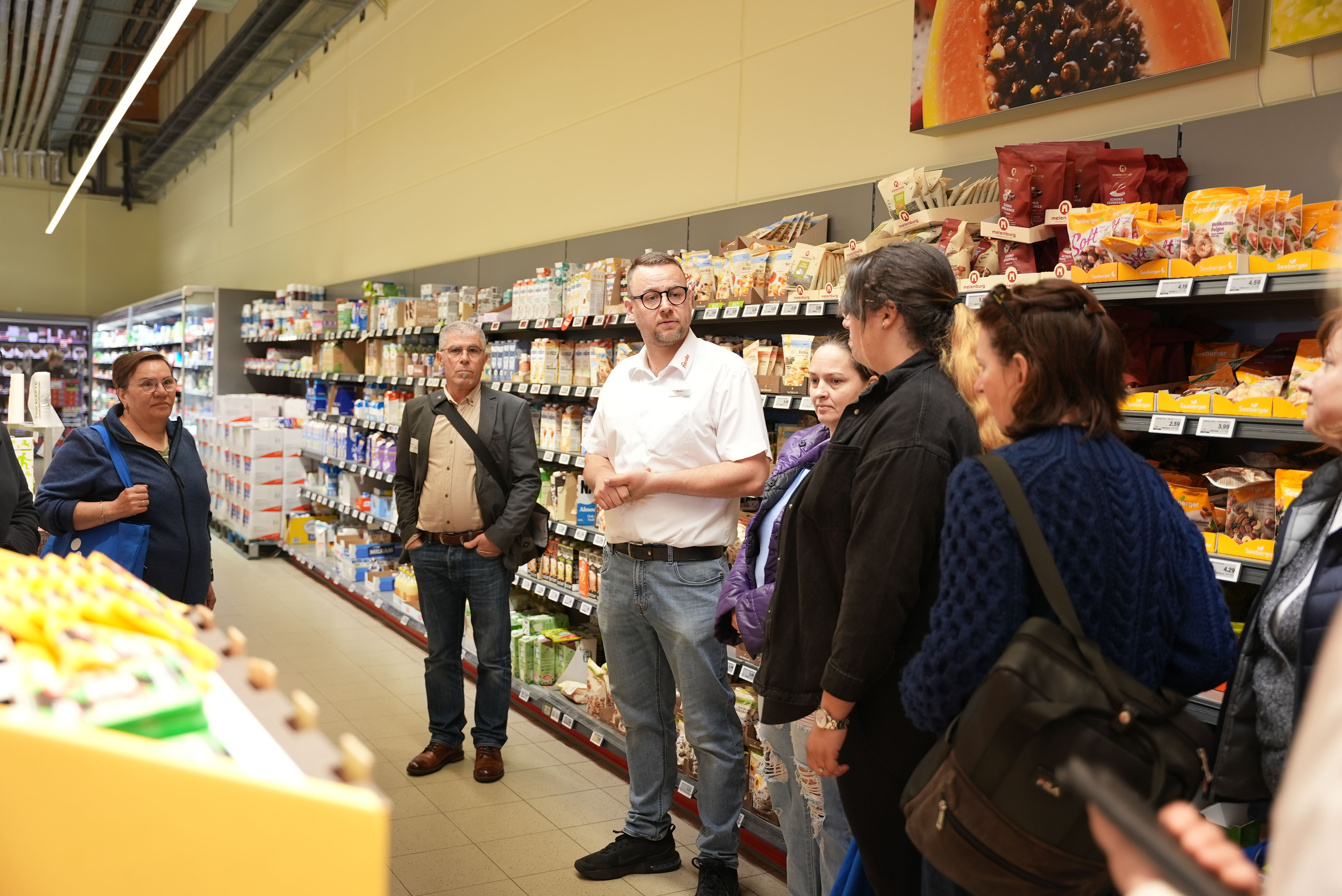 KI generiert: Das Bild zeigt eine Gruppe von Personen, die in einem Supermarkt steht, möglicherweise bei einer Führung oder Besprechung.