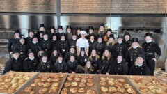 KI generiert: Eine Gruppe von Menschen in schwarzen Uniformen und ein Bäcker posieren vor Öfen und frisch gebackenem Gebäck.