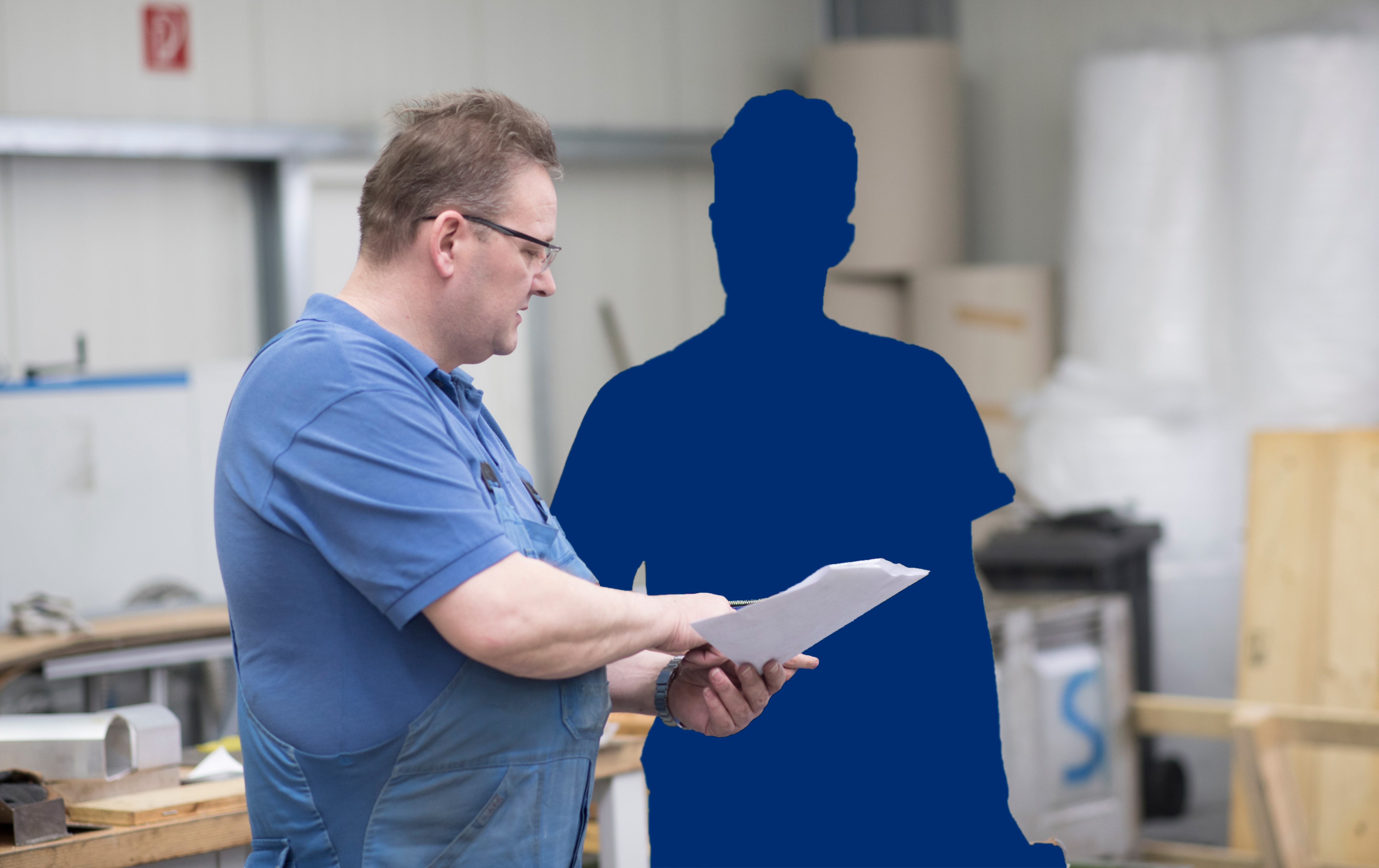 KI generiert: Ein Mann in Arbeitskleidung steht in einer Werkstatt und zeigt auf ein Dokument, während eine blaue Silhouette daneben steht.