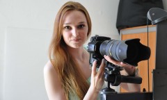 Auszubildende zur Fotografin. Kamera vor ihr auf schwenkbarem Archiv. Hände an Kamera.