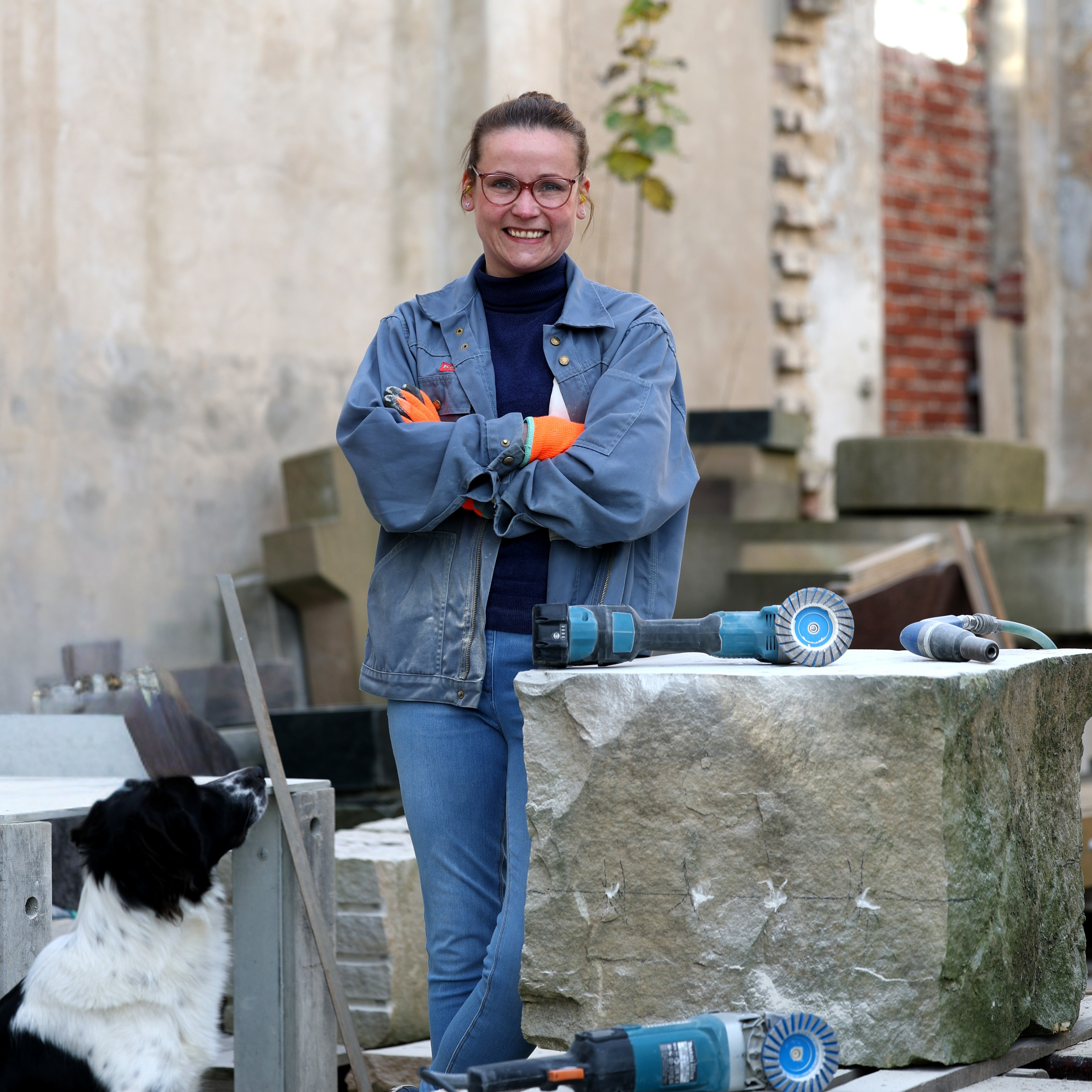 KI generiert: Eine Person steht neben einem großen Steinblock mit Werkzeugen darauf, während ein Hund daneben sitzt.
