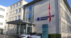 KI generiert: Das Bild zeigt das Gebäude der Handwerkskammer Oldenburg mit einem Hinweisschild und wehender Flagge.