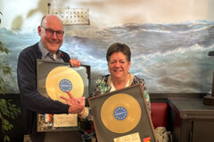 KI generiert: Zwei Personen halten jeweils eine goldene Schallplatte in den Händen.