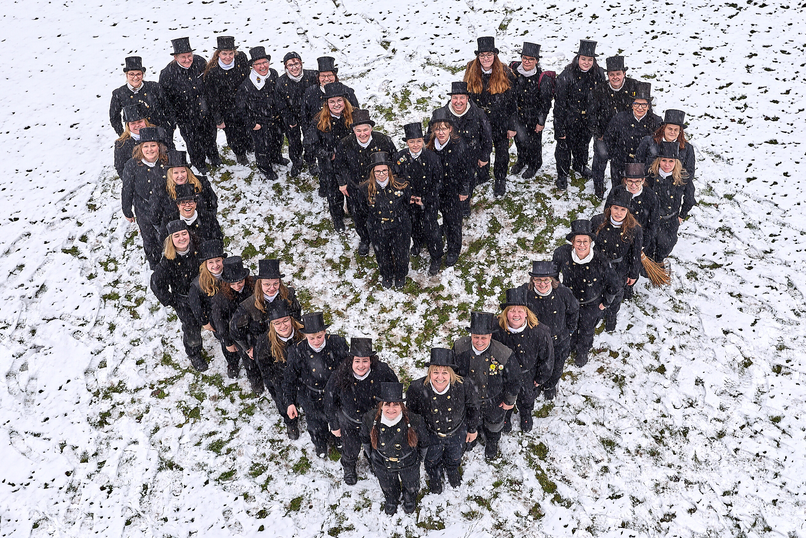 KI generiert: Eine Gruppe von Schornsteinfegern steht im Schnee in einer Herzform.