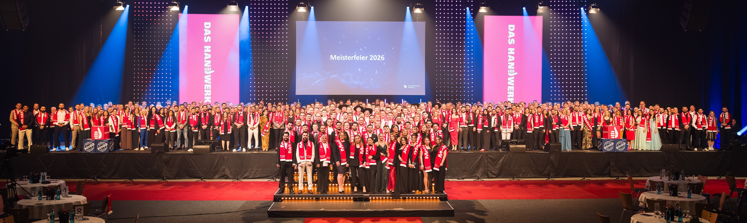 KI generiert: Das Bild zeigt eine große Gruppe von Menschen, die bei einer Veranstaltung namens "Meisterfeier 2026" auf einer Bühne posieren.